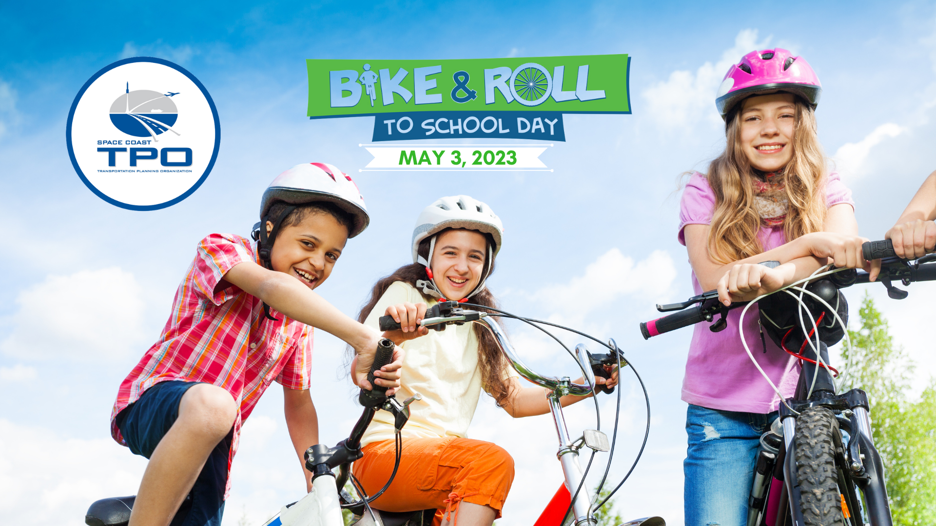 Three students on bicycles smile with a nature landscape behind them.