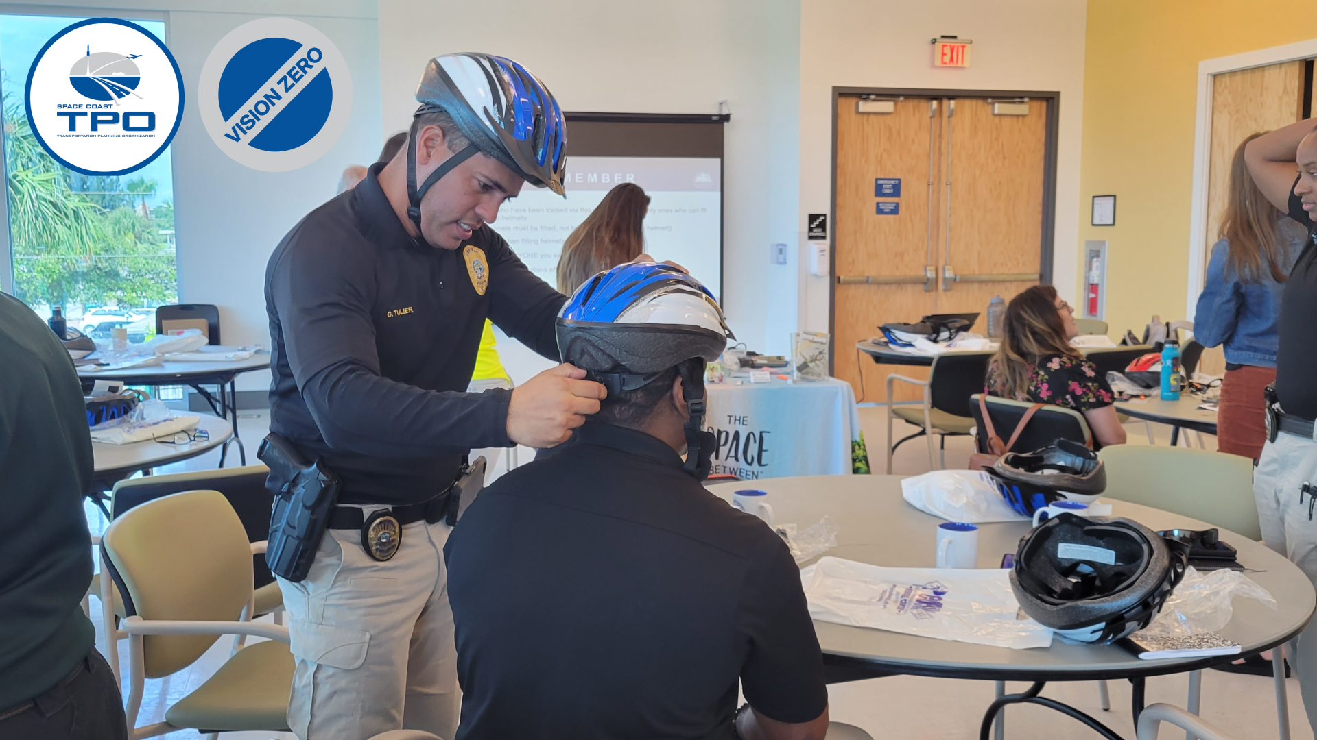 Photo of a police officer fit the other with a bicycle helmet.